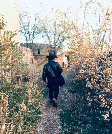 man walking down an overgrown alley