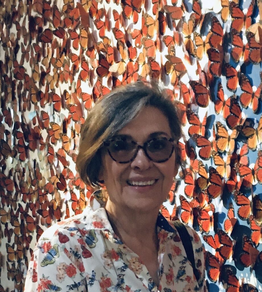 A woman standing in front of a wall covered with butterflies.