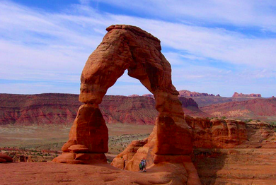 A person standing in front of an arch on top of a hill.