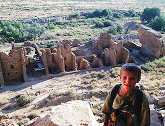 A young boy standing in front of some ruins.