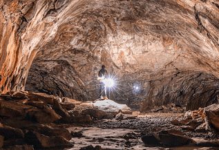 man walking with flashlight in an underground cave