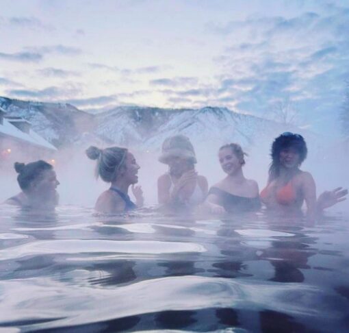 5 ladies soaking in a hot springs pool surrounded by steam