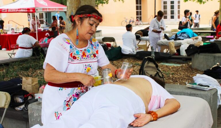 A woman is giving an acupuncture treatment to another person.