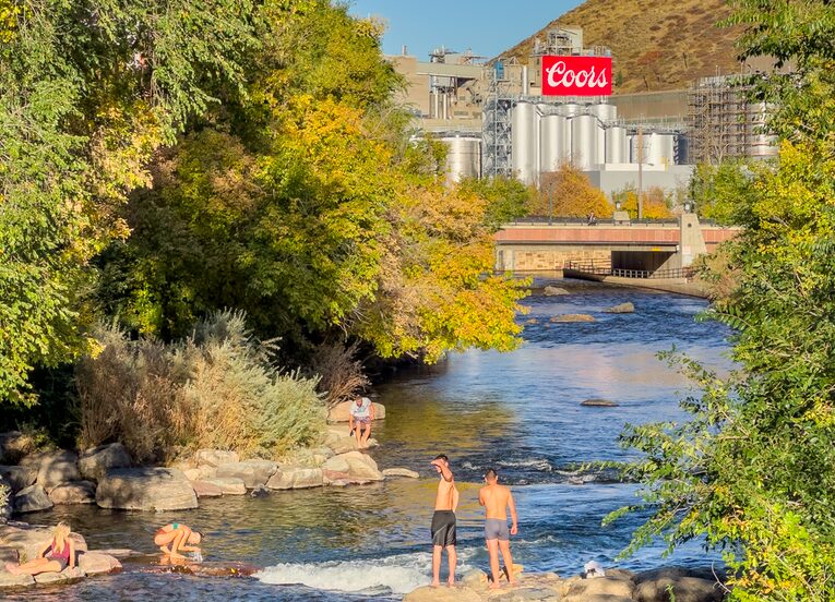 Two people standing in the water near a river.