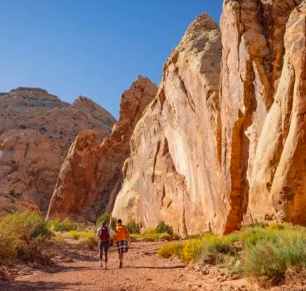 2 people walking down a dusty road in a Utah canyone